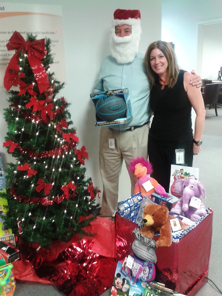Alan Traster, president of Guardian Pharmacy SEFL and Patient Care Pharmacy Services, and Debi Schulman, director of business development of Guardian Pharmacy SEFL, admire the gifts donated by pharmacy employees.